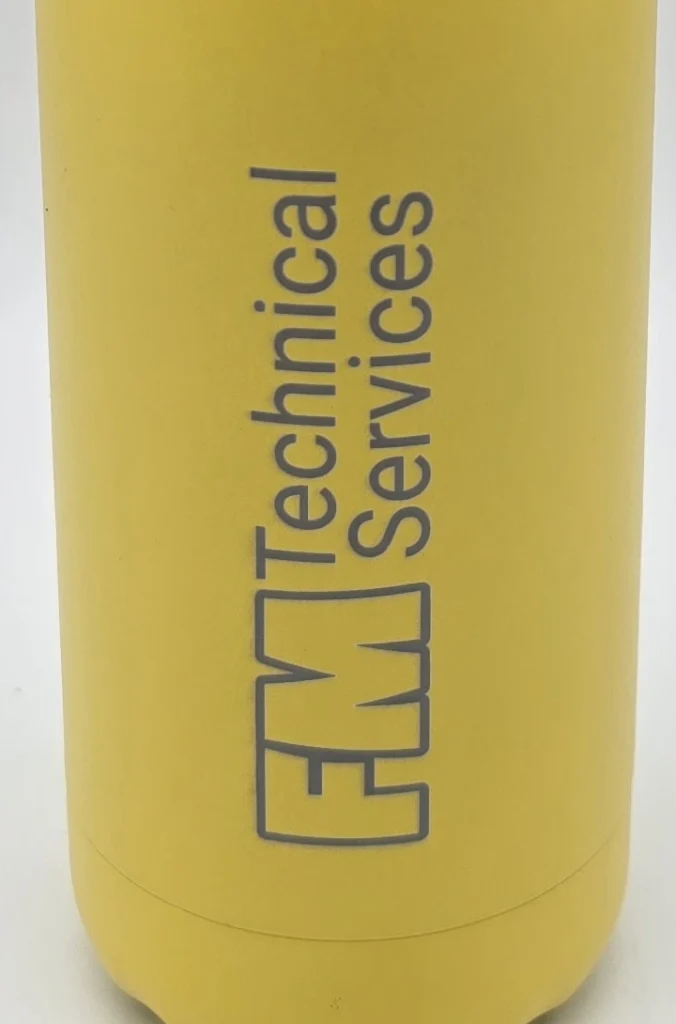 Close-up of the FM Technical Services logo engraved through the yellow coating of an insulated bottle.
