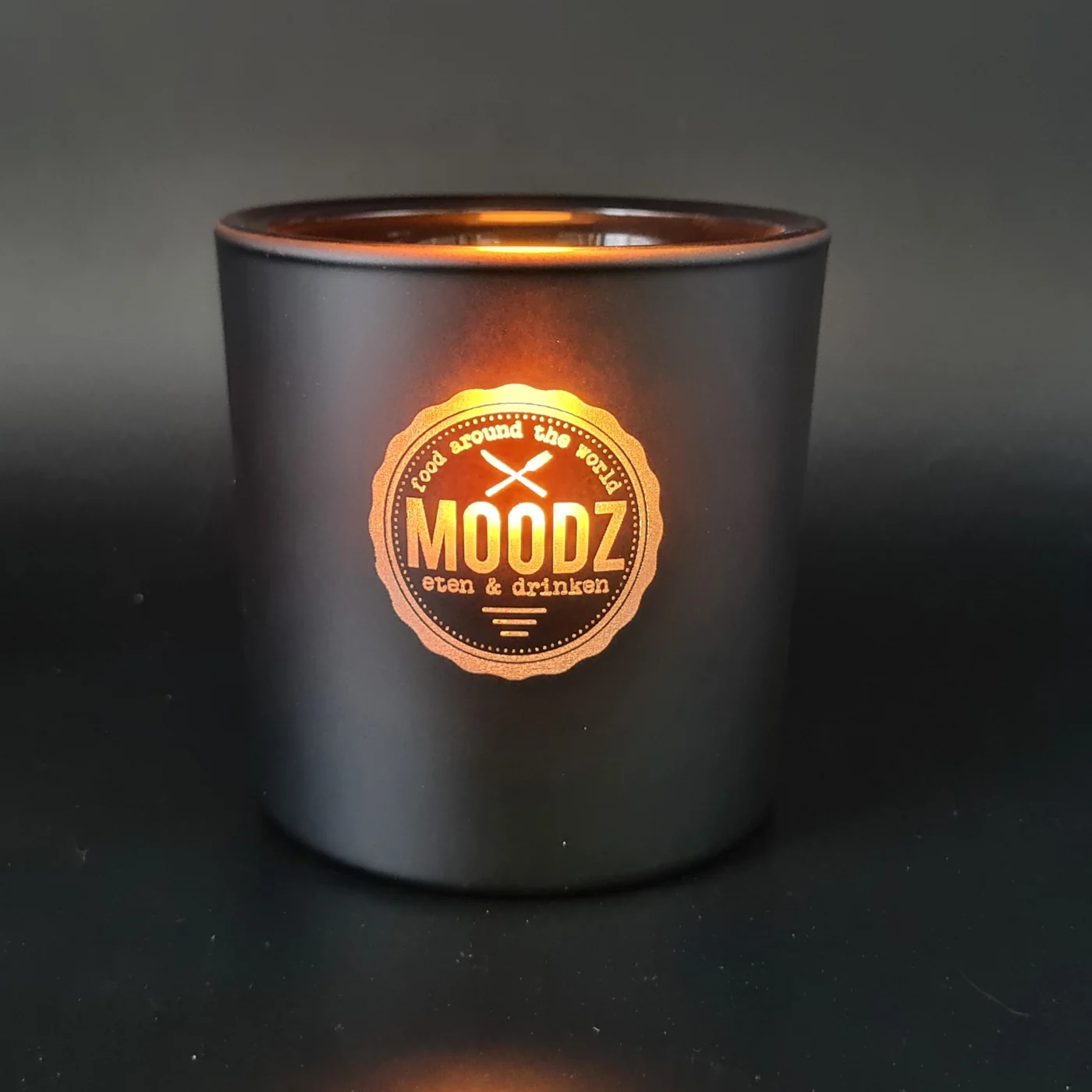 Brandende matzwarte geurkaars met gegraveerd Moodz-logo