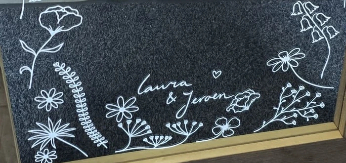 Close-up of the floral engraving and the names Laura and Jeroen at the bottom of the timber-framed mirror.