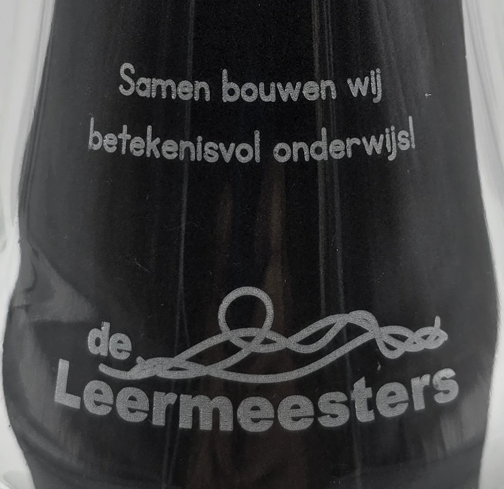 Detail van de glasgravure op de waterkaraf: het logo de Leermeesters en Samen bouwen wij betekenisvol onderwijs!