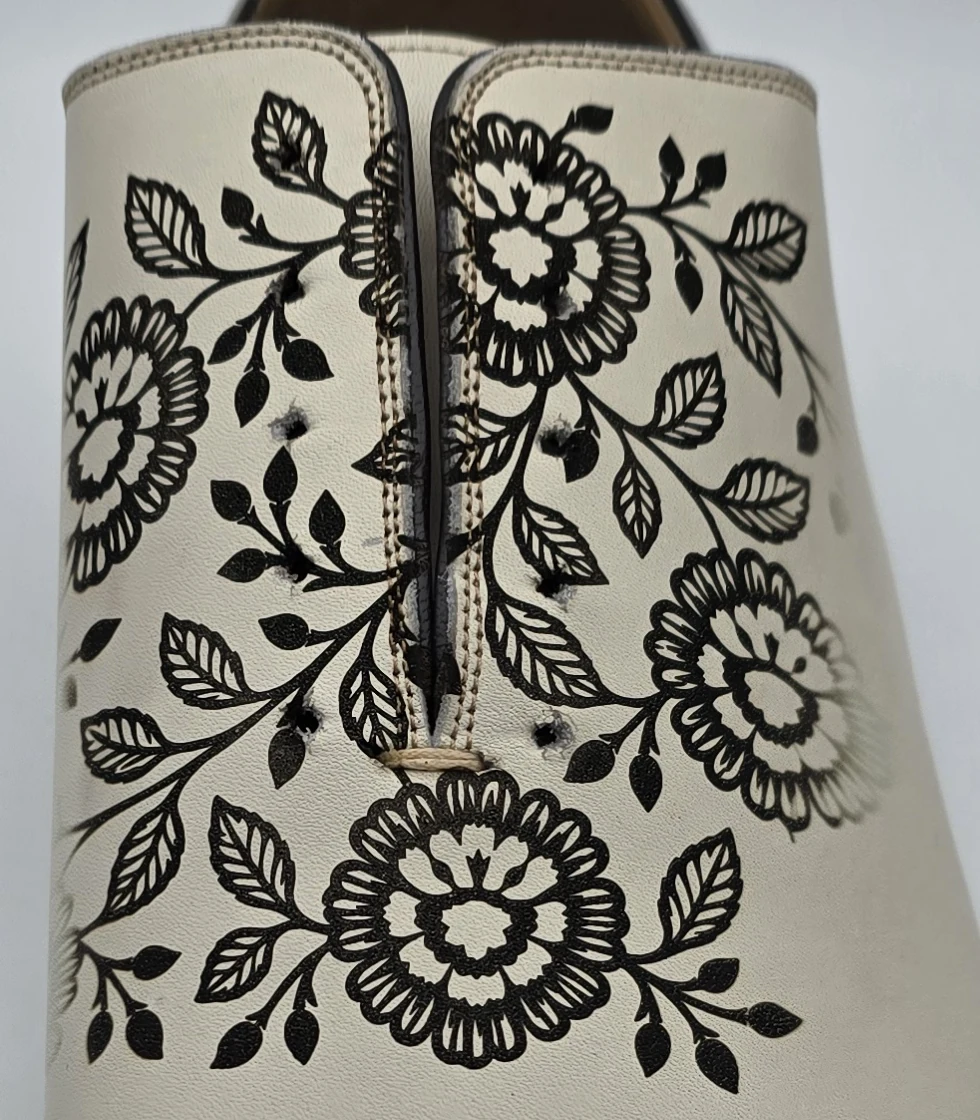 Wedding shoe engraving detail with floral motifs beside the centre seam of the uncoloured leather shoe