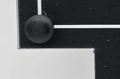 Close-up of the black corner fixing and white engraved border on the memorial plaque made for Jan Elzinga.